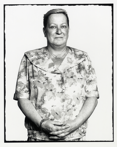 108354 Portret van een vrouw met een gebloemd pakje aan en de handen gevouwen voor haar buik.